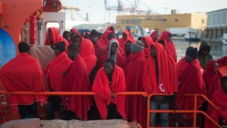 Migrants are seen standing on a rescue boat as they wait to disembark after their arrival at the Port of Malaga, Spain
