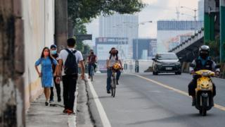 People walk and ride bicycles to work along a highway in Makati, Philippines, 04 August 2020.