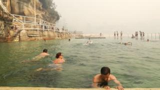 Swimmers at a Sydney beachside pool amid the smoke on Tuesday morning