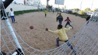 Libyan youths play a game of football on a sand pitch in the capital Tripoli, on 3 February 2020