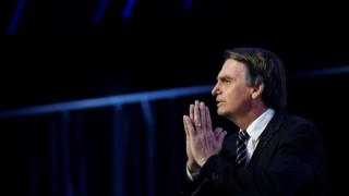 Jair Bolsonaro, de perfil, com as mãos juntas em frente ao rosto