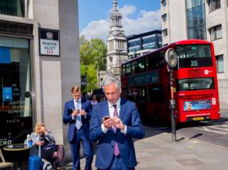 City workers check their phone. St Paul's, London.