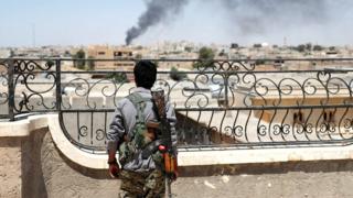 Un combatiente kurdo observa Raqqa justo después de un ataque aéreo sobre la ciudad.