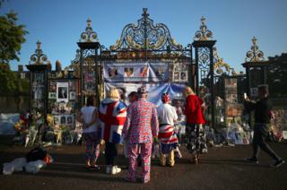 Members of the public look at flowers and tributes left in memory of the late Princess Diana