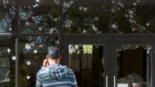 Hombre frente a ventana con balazos