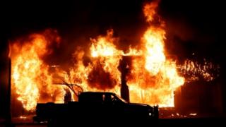 Während einer Demonstration gegen den Tod in Minneapolis wird ein Auto vor einem Feuer gesehen