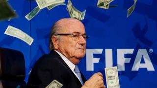Sepp Blatter entouré de billets en dollars qui lui étaient lancés par le comédien Simon Brodkin lors d'une conférence de presse au siège de la FIFA le 20 juillet 2015 à Zurich.