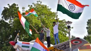 Indian residents hold flags on a model of a military plane to celebrate the air strike launched on February 26, 2019