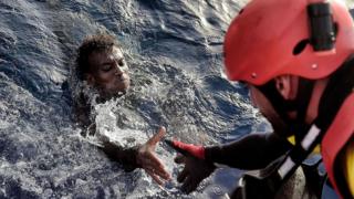 Un inmigrante recibe ayuda de un rescatista