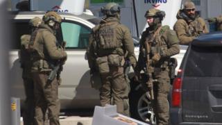 Members of the Royal Canadian Mounted Police (RCMP) tactical unit confer after encountering the suspect in a deadly shooting rampage