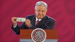 AMLO muestra su billete de dos dólares.