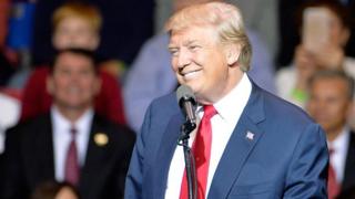Donald Trump ariko arashikiriza ijambo i Crown Coliseum mu kwezi kwa cumi na kabiri itariki 6 mu 2016 mu karere ka la Fayetteville, North Carolina.
