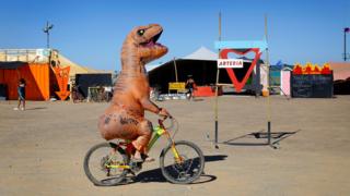 A Burner rides his bicycle wearing a dinosaur costume during the annual Afrikaburn Festival held in the Tankwa Karoo, Calvinia, South Africa