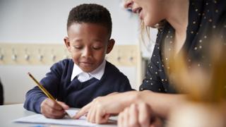 Pupil writing with teacher