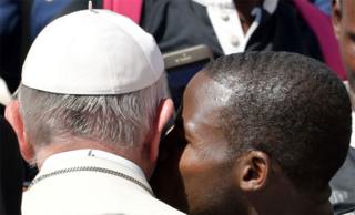 A member of a rugby team kisses Pope Francis