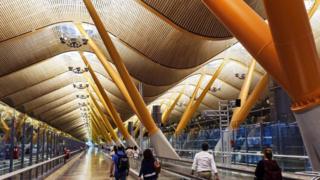 Pessoas caminham em corredor de aeroporto