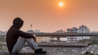 Young male sitting on a rooftop looking out