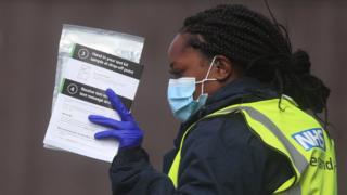 An NHS test and trace worker keeps a self-test kit at a testing center in Bolton
