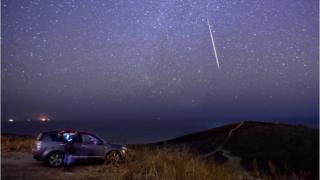 A stargazer watching a meteor into the sky