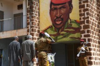 Burkina Faso's President Roch Marc Christian Kabore (left) and Ghana's former President Jerry Rawlings (centre) stand under the portrait of Burkina Faso's former President Thomas Sankara at the entrance of the house where he was killed in 1987, during the inauguration of his memorial at the Conseil de l'Entente in Ouagadougou.