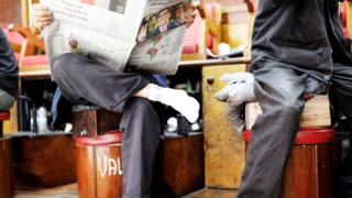 Homem lê jornal que mostra foto de Bolsonaro