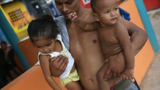 Un joven sostiene a una niña y un niño