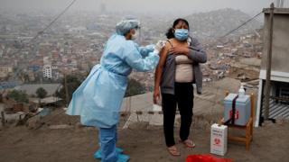 A nurse from gives a resident flu and pneumonia vaccines in Lima, Peru.