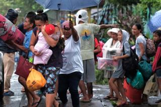 Villagers carry belongings as they are evacuated in anticipation of an approaching typhoon in Legaspi city, Albay province, Philippines, on 2 December 2019