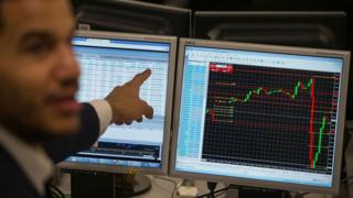 A trader points to a the trading terminal screen showing the S&P 500 Index, as he works at ETX Capital in central London on November 9, 2016, following the result of the US presidential election