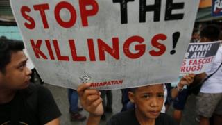 Филиппинский сочувствующий держит плакат, присоединяясь к похоронам студента Киана Делоса Сантоса, на улице в Маниле, Филиппины, 26 августа 2017 года