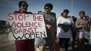 Women hold signs during a protest against ongoing violence against women, in Gugulethu, on May 21, 2016, about 20 Km from the centre of Cape Town.