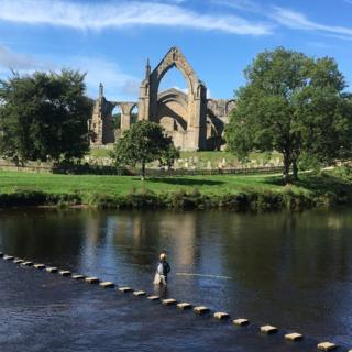 The stepping stones across the River Wharfe, alongside the ruins of Bolton Abbey in Wharfedale, North Yorkshire