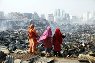Three women look at the destroyed homes