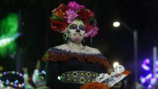 A woman dressed as a Mexican catrina poses for a photo in Medellín