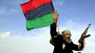 A rebel soldier gestures atop a car as he heads to Brega, in Ajdabiya March 2, 2011.