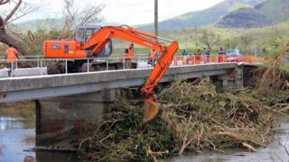 An excavator on a bridge removing uprooted trees from a river following Cyclone Winston in Fiji's western division (22 February 2016)