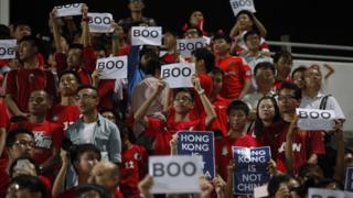 Hong Kong fans hold up signs that read 'Boo' while the national anthem was being played during a world cup qualifier at Mong Kok stadium in Hong Kong on November 17, 2015.