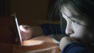 Adolescente frente a una pantalla de celular