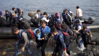Сирийские и афганские беженцы спрыгивают с лодки и прибывают на греческий остров Лесбос