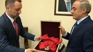 Picture from the Syrian president's Facebook page shows a representative of Syria's foreign affairs giving the Legion d'honneur Grand Croix award to a representative from the Romanian embassy. April 19, 2018