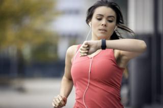 Žena džogira i gleda u uređaj za fitnes podatke na ruci