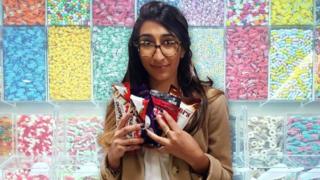 Una mujer con muchos chocolates y dulces en la mano