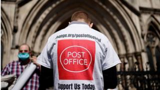 A supporter celebrates outside the Royal Courts of Justice in London, on April 23, 2021, following a court ruling clearing subpostmasters of convictions for theft and false accounting.
