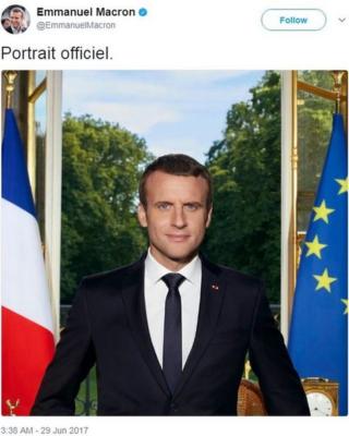 Президент Франции написал в Твиттере свой официальный портрет, на котором он стоит перед столом, за которым открывается окно в сад. Он в окружении французского флага слева и флага Европейского союза справа.
