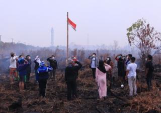 Sekelompok pemuda menggelar upacara bendera di area lahan gambut yang masih terbakar di Palangka Raya, Kalimantan Tengah, Sabtu (17/8/2019)