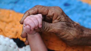 A Pakistani woman holds the hand of her grandchild