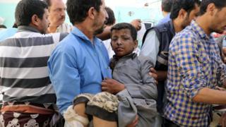 A Yemeni man holds a boy injured in an air strike in Saada (9 August 2018)
