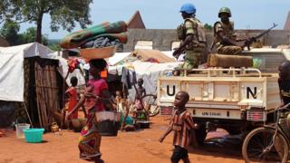 A woman and a child walk past UN peacekeepers from Gabon patrolling the Central African Republic town of Bria on June 12, 2017