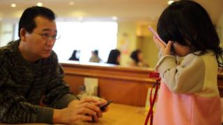 Baby and her dad busy with smartphones