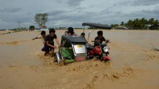 Residents push a tricycle on a flooded road in Santa Rosa town, Nueva Ecija province